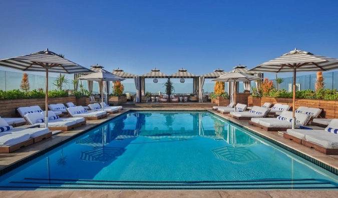 An expansive rooftop pool surrounded by umbrellas and loungers at the Sixty Beverly Hills hotel in LA