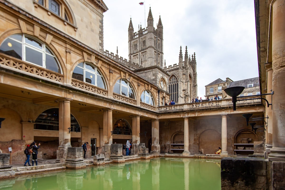 The vivd green waters of the old roman bath complex contrast with the limestone pillars