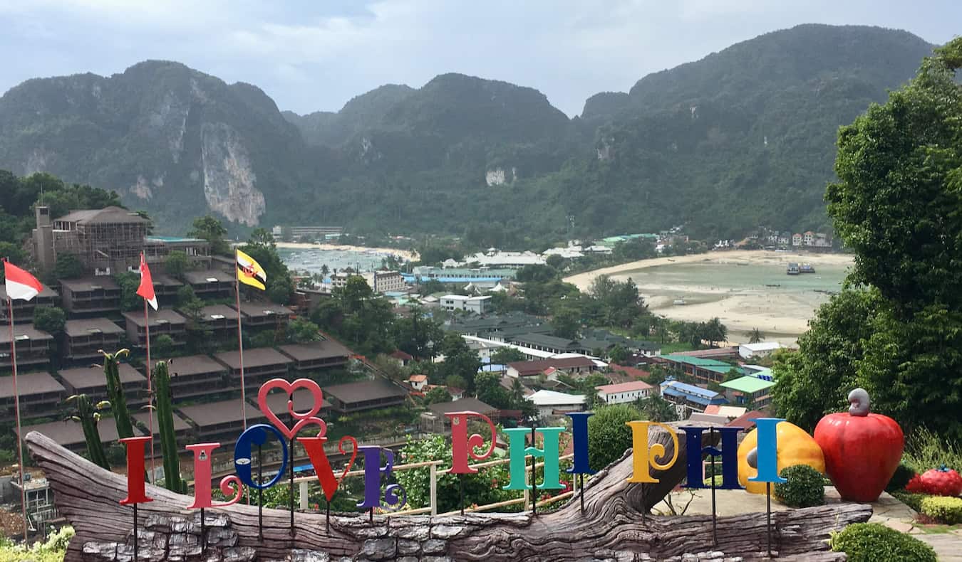 A sign welcoming visitors to Ko Phi Phi, Thailand with lush, green hills filling the background